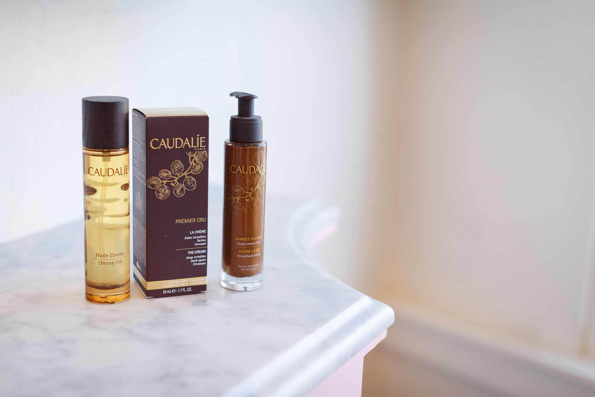A counter with two bottles of oil and a bottle of lotion.