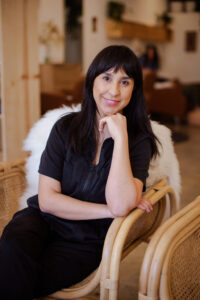 A woman sitting on top of a chair in front of a window.