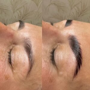 A woman with long eyelashes is getting her brows tattooed.