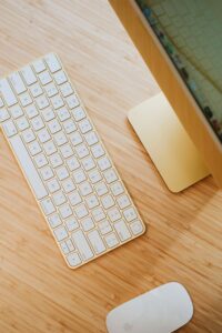 A keyboard and mouse on top of a wooden table.