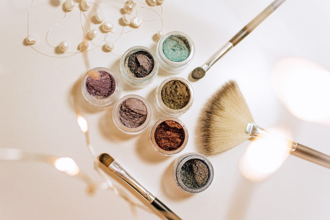 A table with makeup brushes and some different colors of eye shadows.