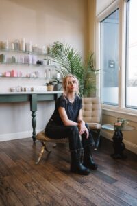 A woman sitting on top of a chair in front of a window.