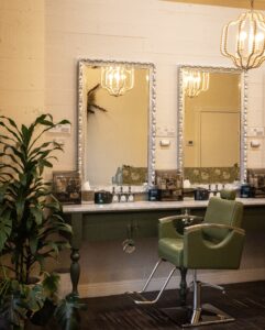 A green chair in front of two mirrors.