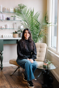 A woman sitting on a chair in front of a window.