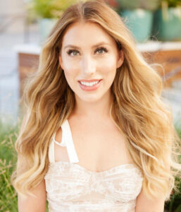 A woman with long blonde hair wearing white.