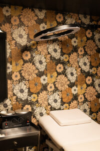 A room with a floral wallpaper and a black wall.